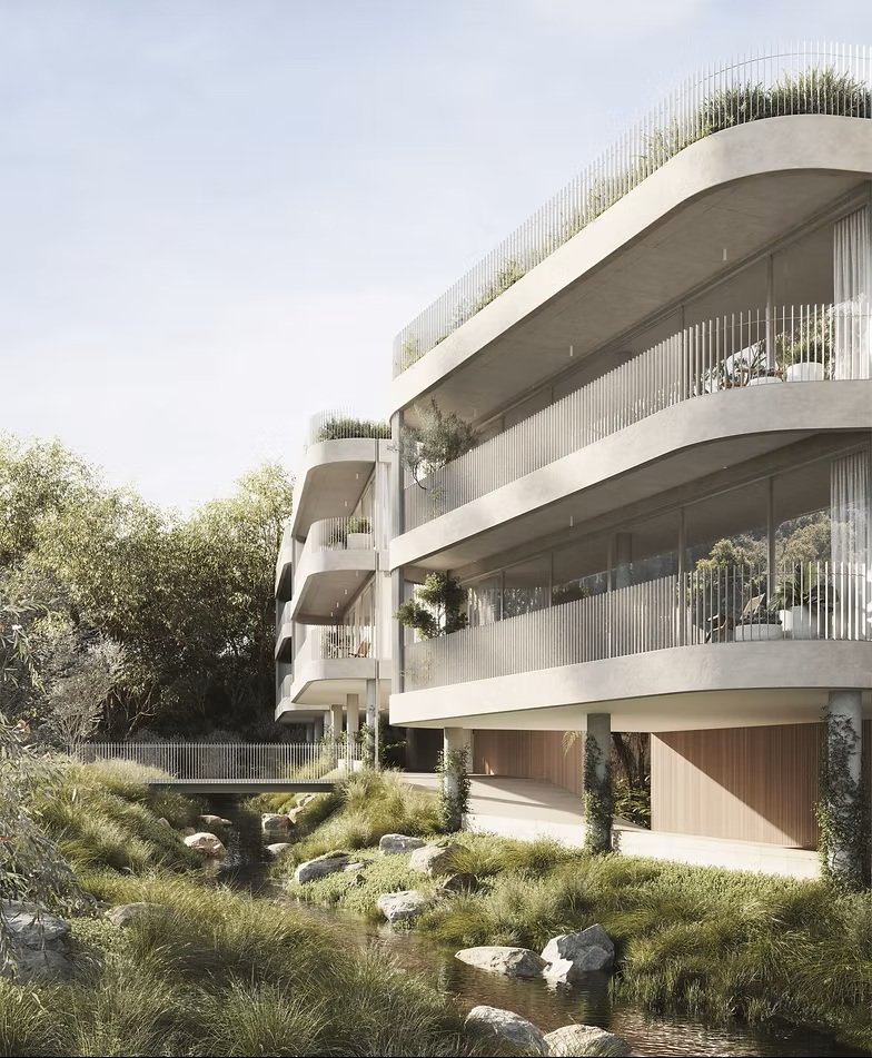 An architectural rendering of a modern apartment building with curved concrete balconies overlooking a natural creek. The design features integrated greenery, thin vertical balustrades, and a pedestrian bridge placed over a restored riparian environment.