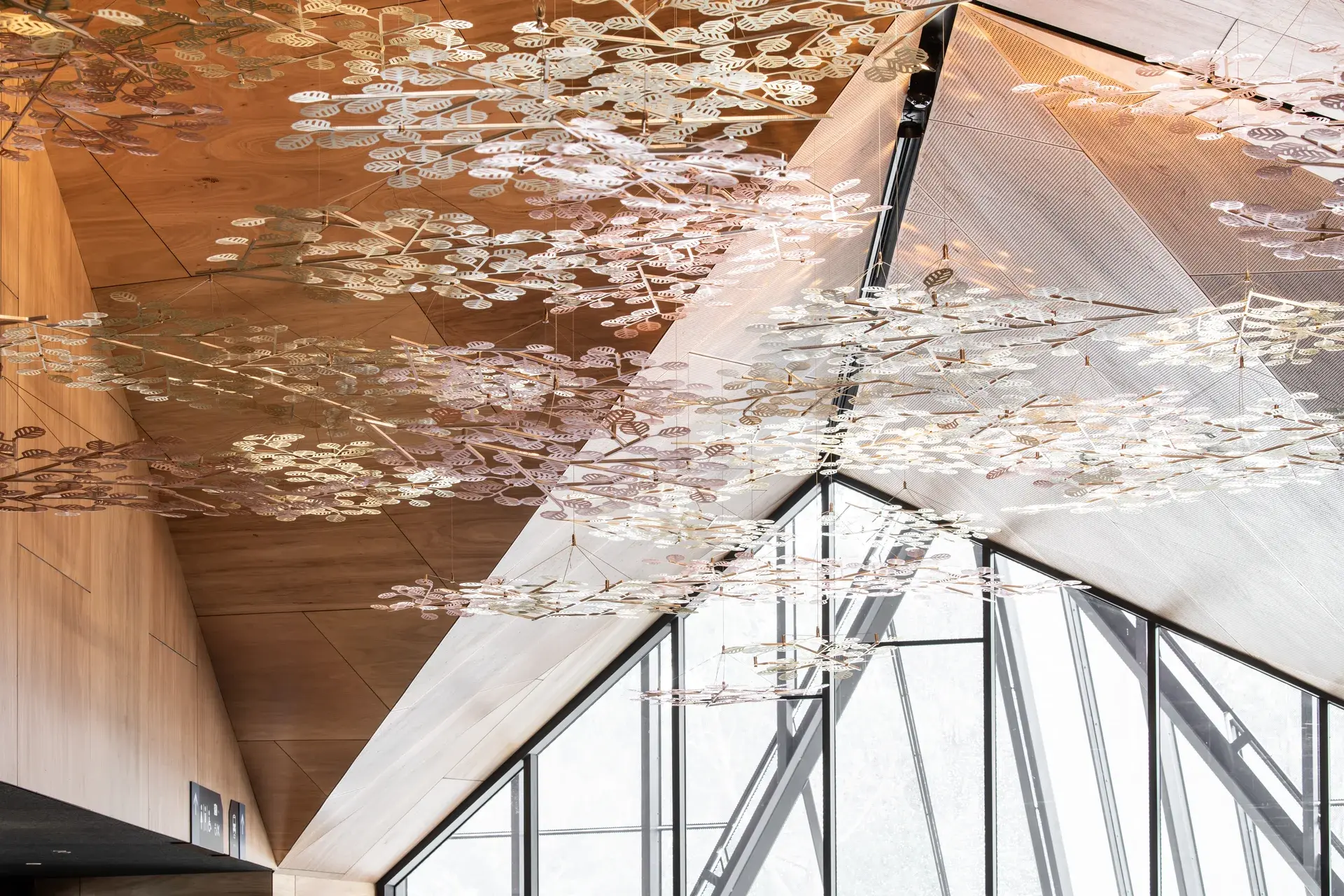 Alex Miles suspended brass fagus sculpture reflects the daylight streaming in from large triangular geometric windows behind.