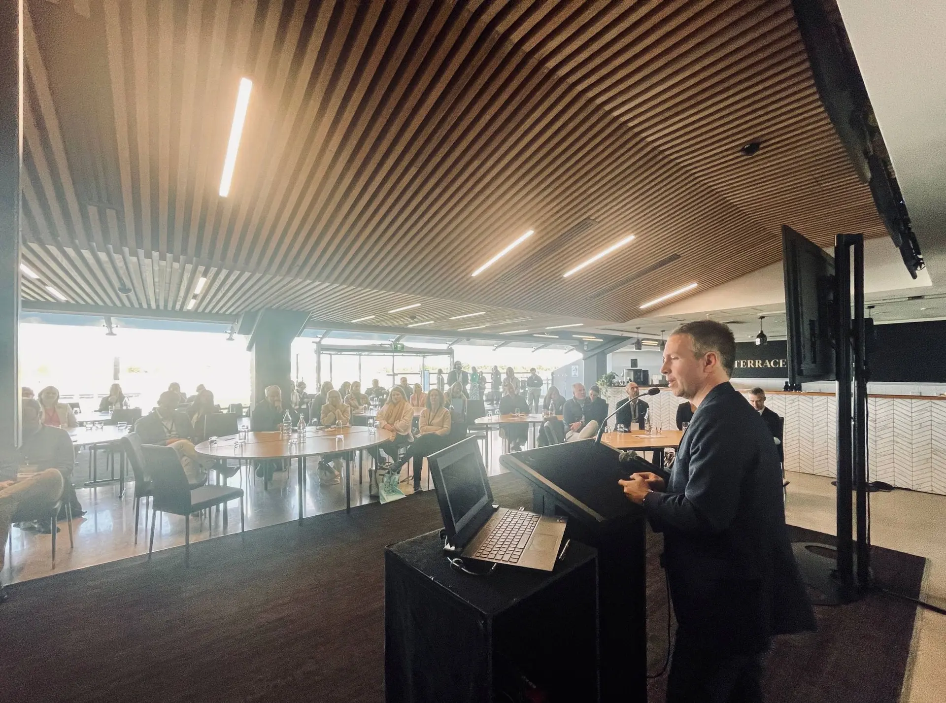 Architect Jet standing behind lectern presenting to a room of people from the South Australian tourism industry.