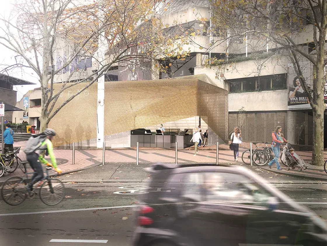 Protagonist cafe in Melbourne's Arts Precinct, showing the gold mesh pavilion integrated into the busy sidewalk with cyclists, cars, and pedestrians passing by.