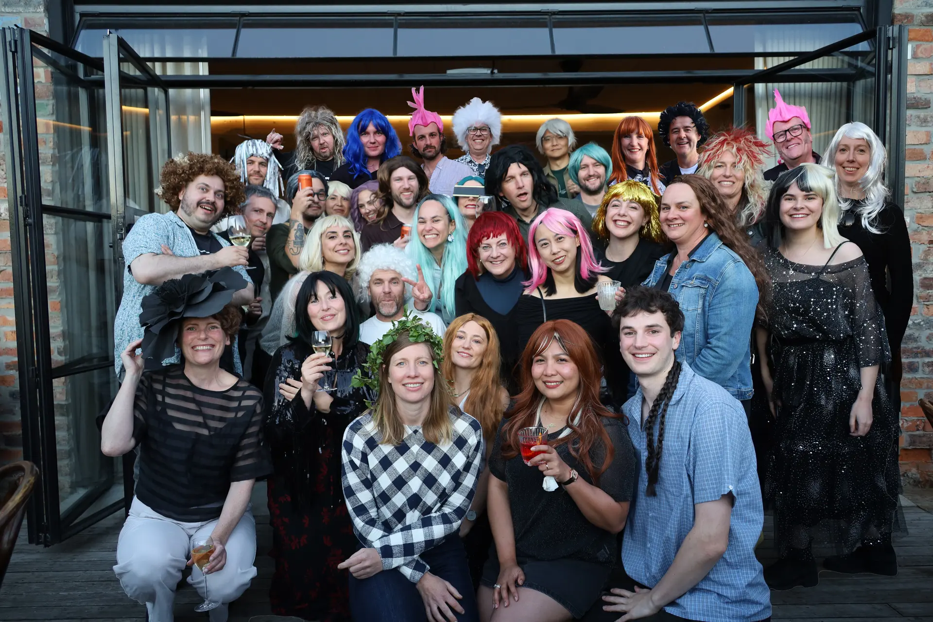 The team at Cumulus gathered together, all wearing an assortment of different wigs and headpieces with large smiles on their faces.