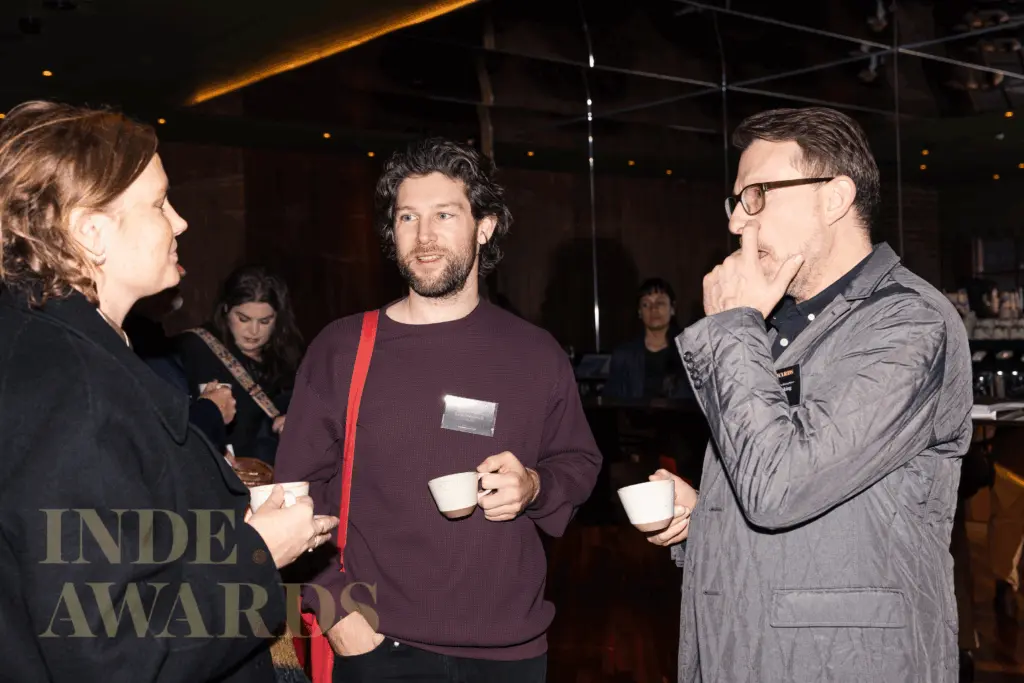 An image of Keith Westbrook in discussion with two other people, all holding small cups.