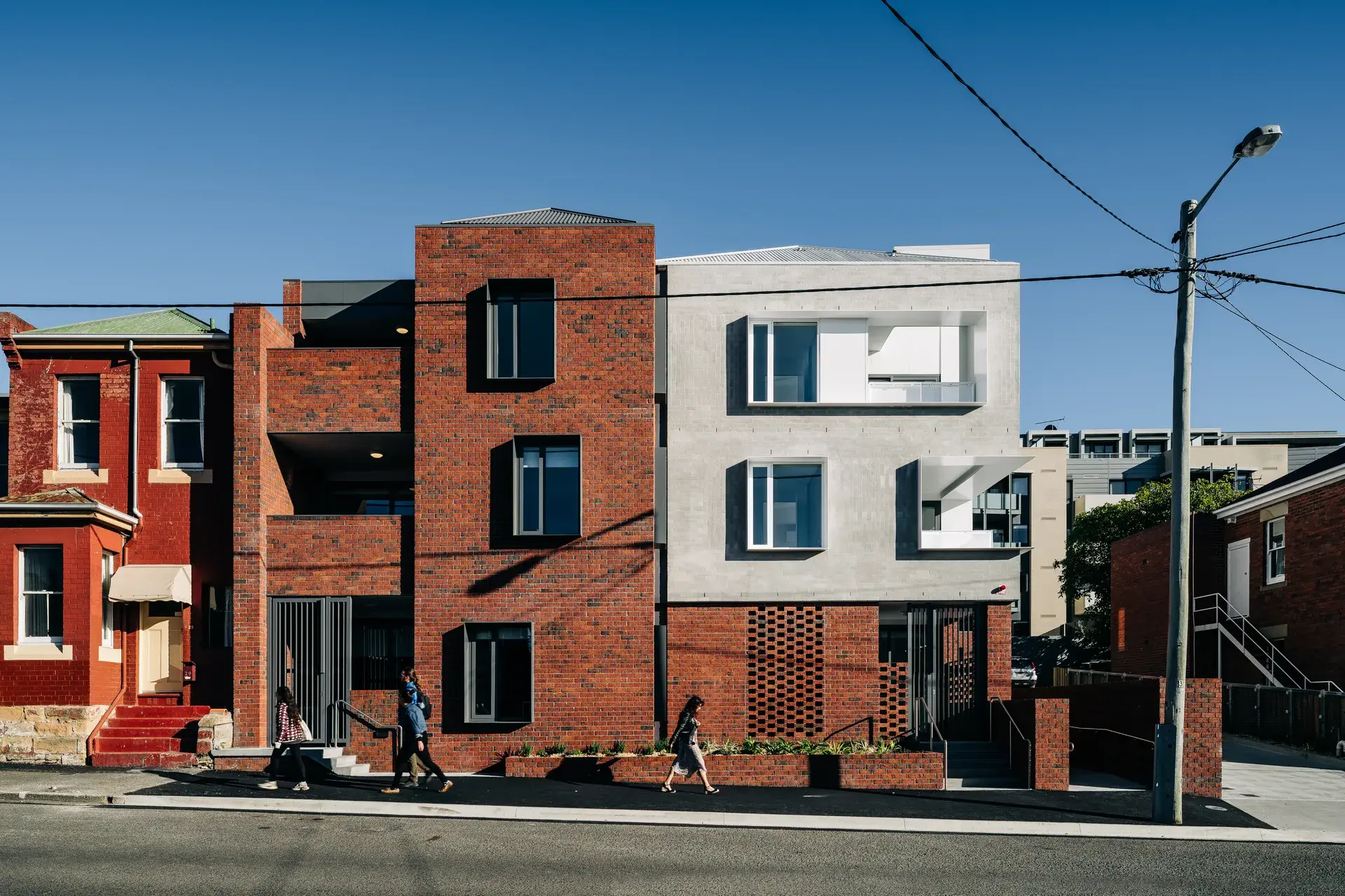 Exterior view of Goulburn Street Housing featuring a combination of red brickwork and grey brickwork, integrated into a street with traditional brick architecture.