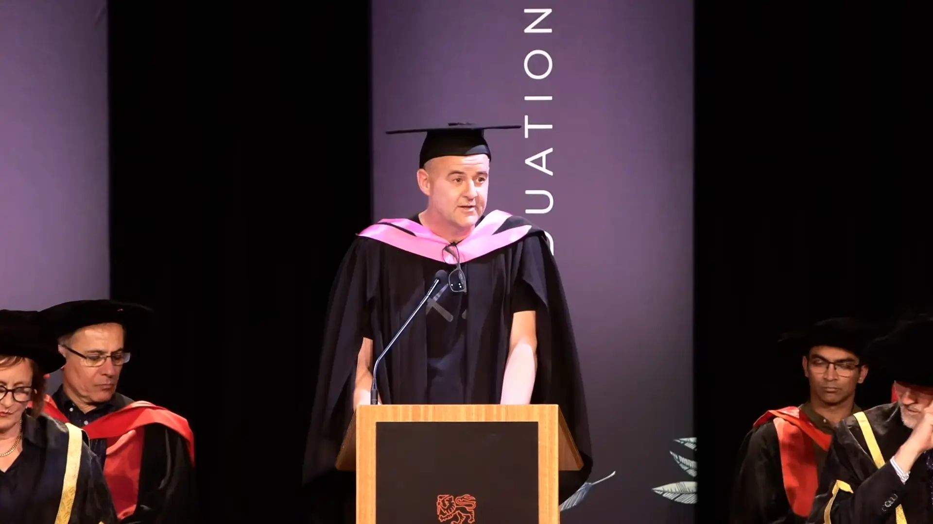 Todd giving his occasional address at the lectern for University of Tasmania's graduation ceremony.