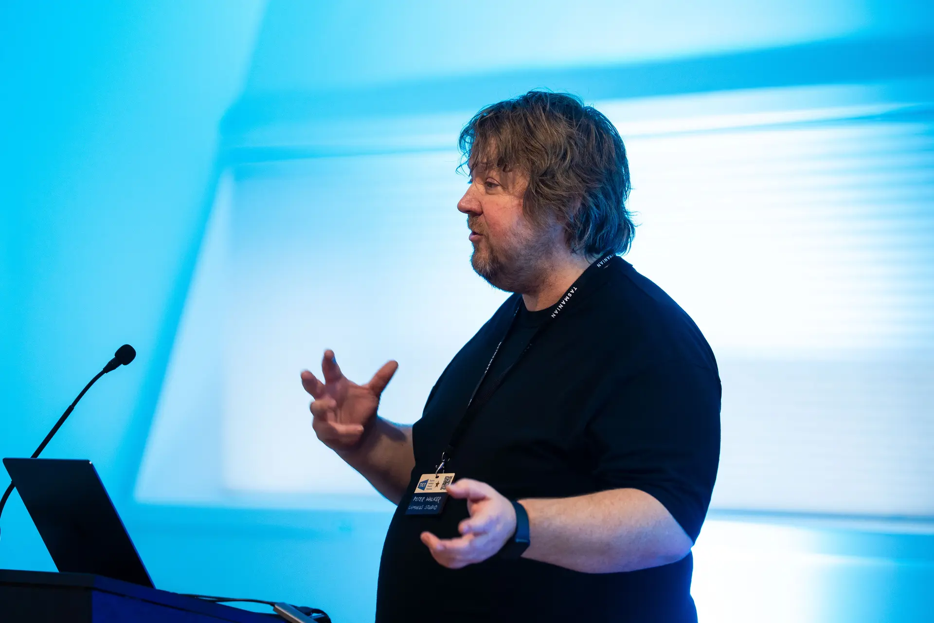 Man in a black shirt presenting at a lectern