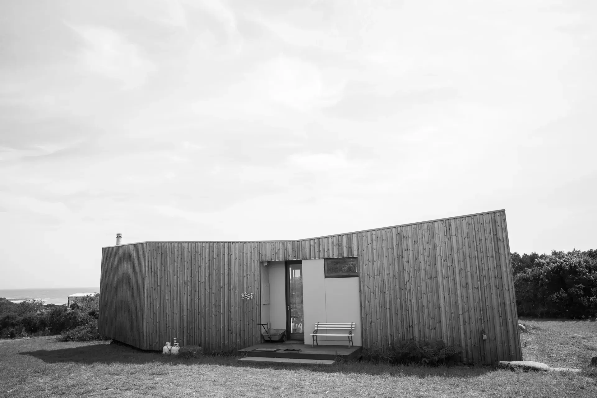A black and white photograph of the vertical timber clad facade of the main entry..