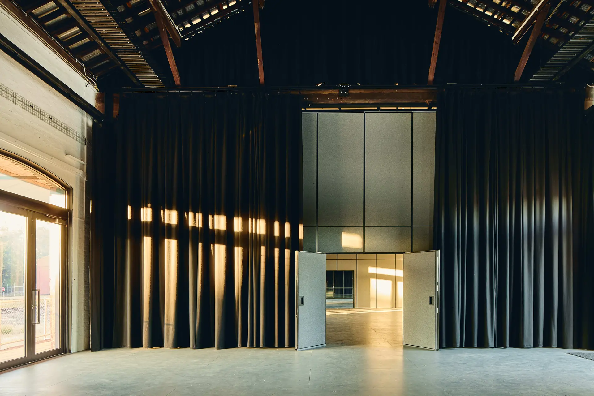 Full-height operable walls provide flexibility for changing needs, while glazed infills above, framed within the existing roof trusses, create end-to-end visual connections and a sense of openness throughout the interior.