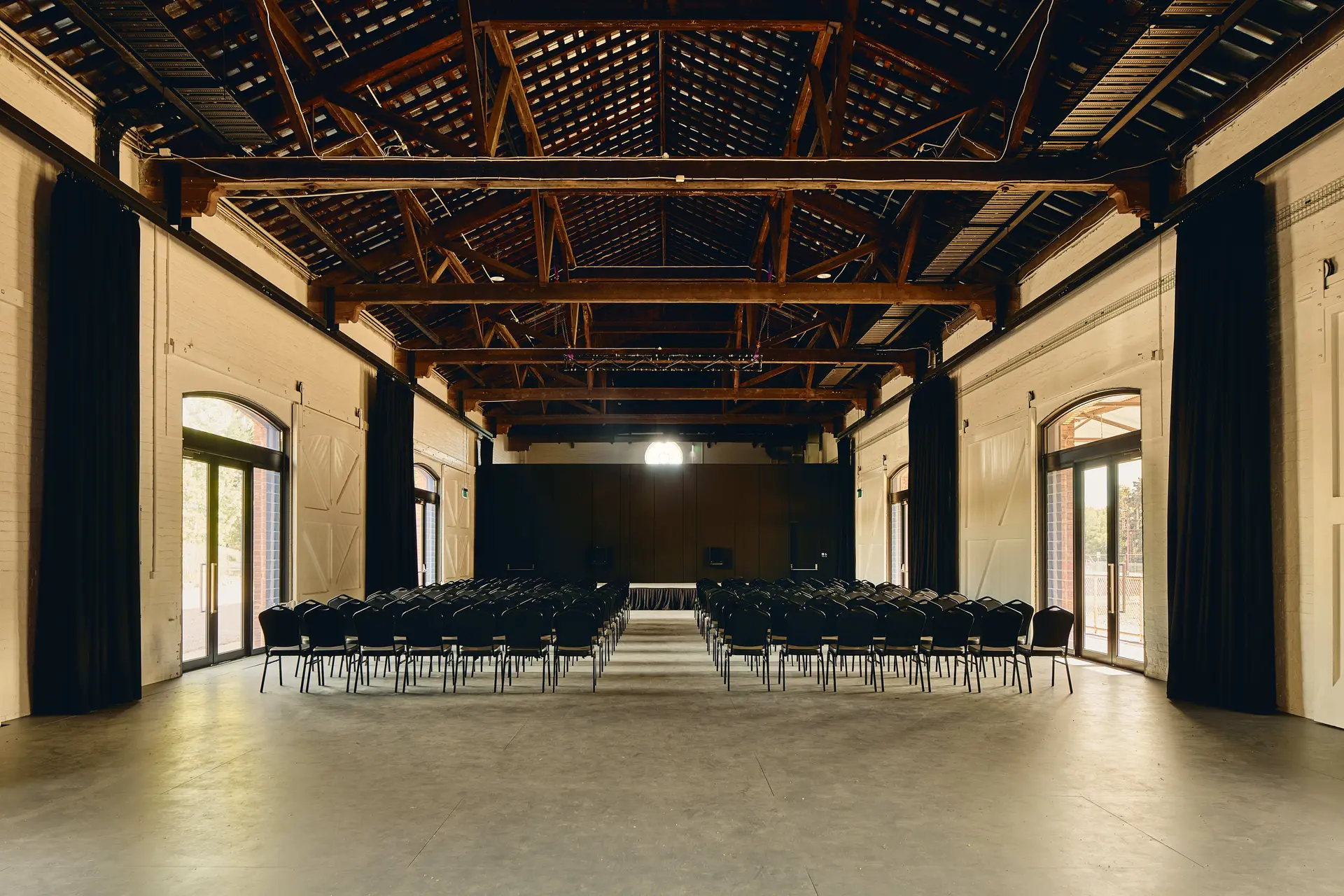 Sunlight streams through the central circular heritage window, filtered by side glazed insertions, illuminating the performance space and evoking history and renewed purpose.