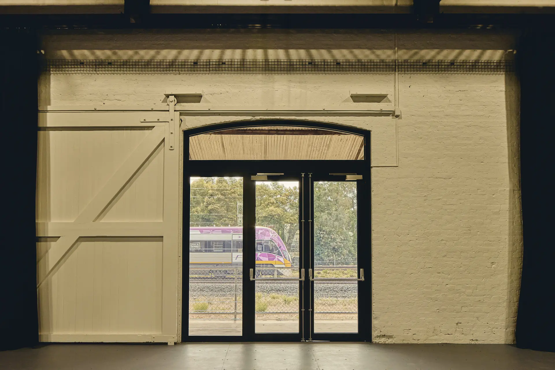 New glazed infills added to existing openings, with retained heritage doors, hinting at its past as a rail freight store as trains pass by.