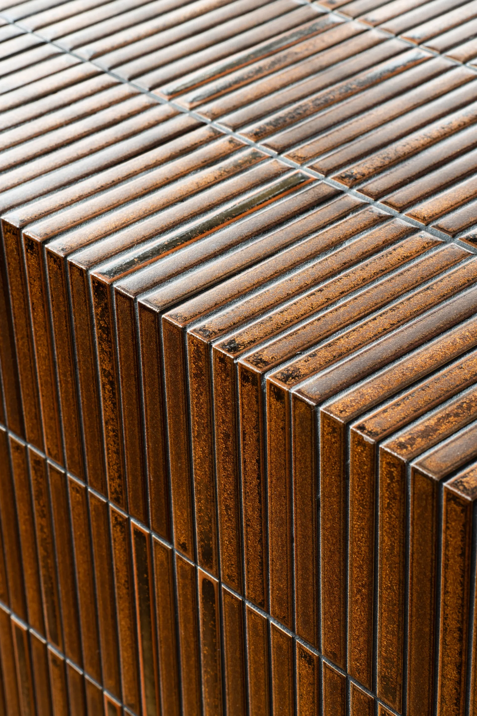 Close up of kitchen island edge, fully covered with textured finger tiles of a rich textured terracotta colour