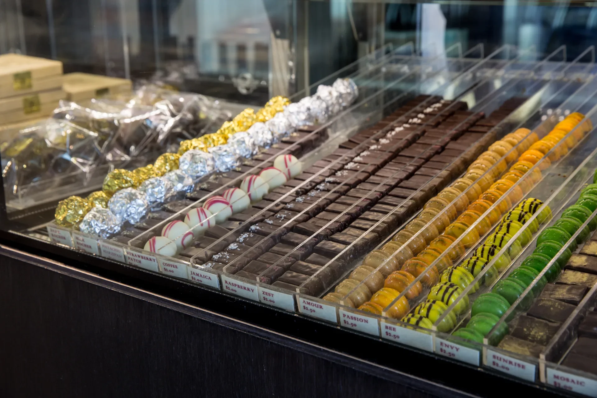 A display of rows and rows of exquisite, brighly decorated handmade chocolates available for visitors to purchase.