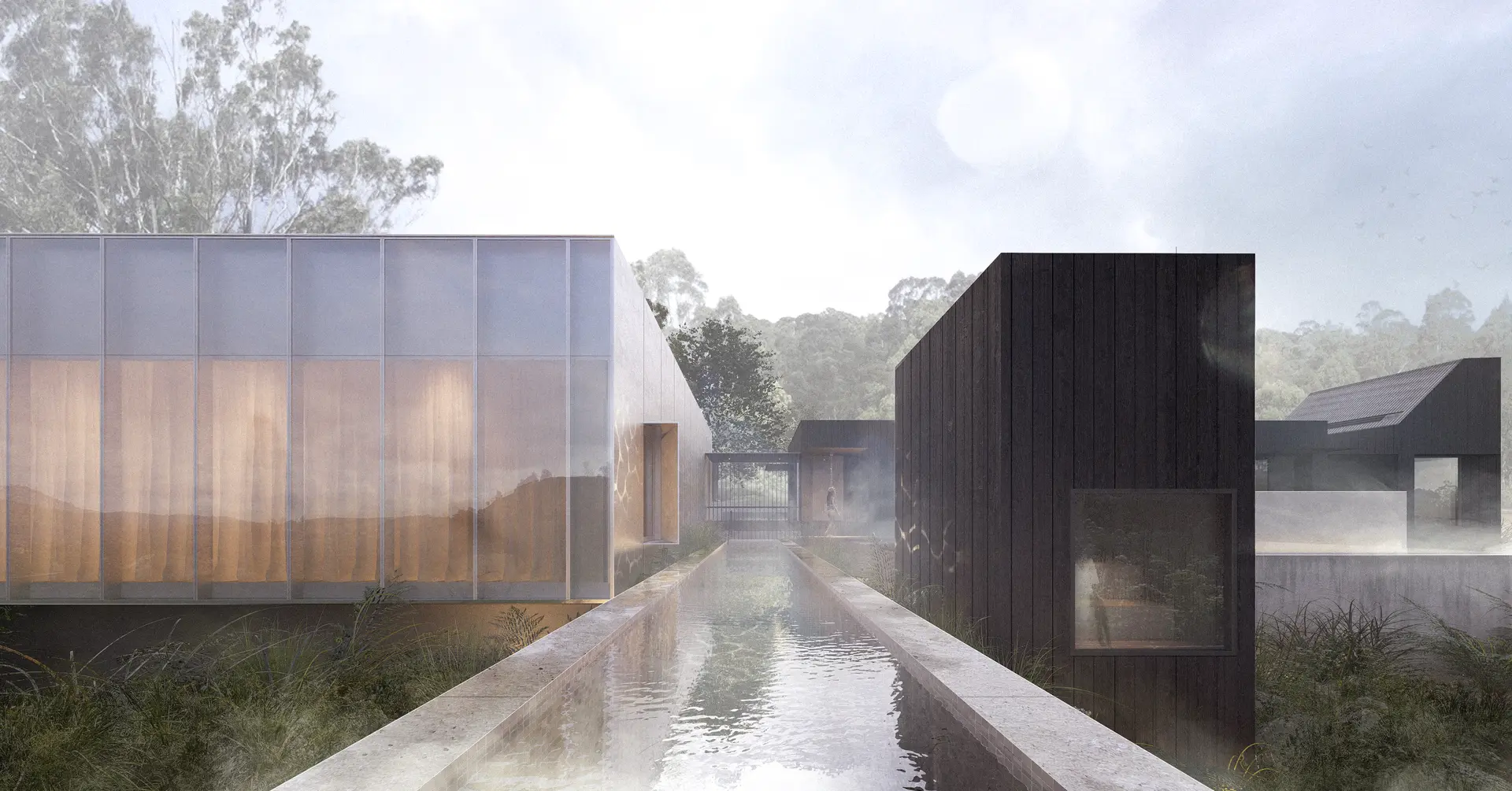 An elongated rectilinear mineral pool lined in small beige square tiles cuts through the site, forming a central axis between buildings – views into neighbouring structures show the yoga studio and steam room in use, with an outdoor shower at the rear. The reflective surface of the pool mirrors the surrounding volumes, guiding movement through the wellness centre and connecting the dispersed structures.
