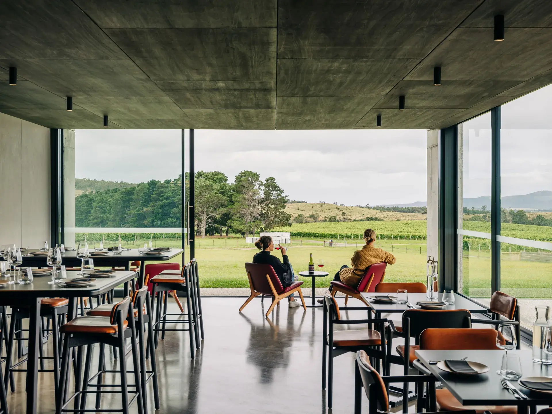 Visitors with the new restaurant space looking out across the bright green vineyard.