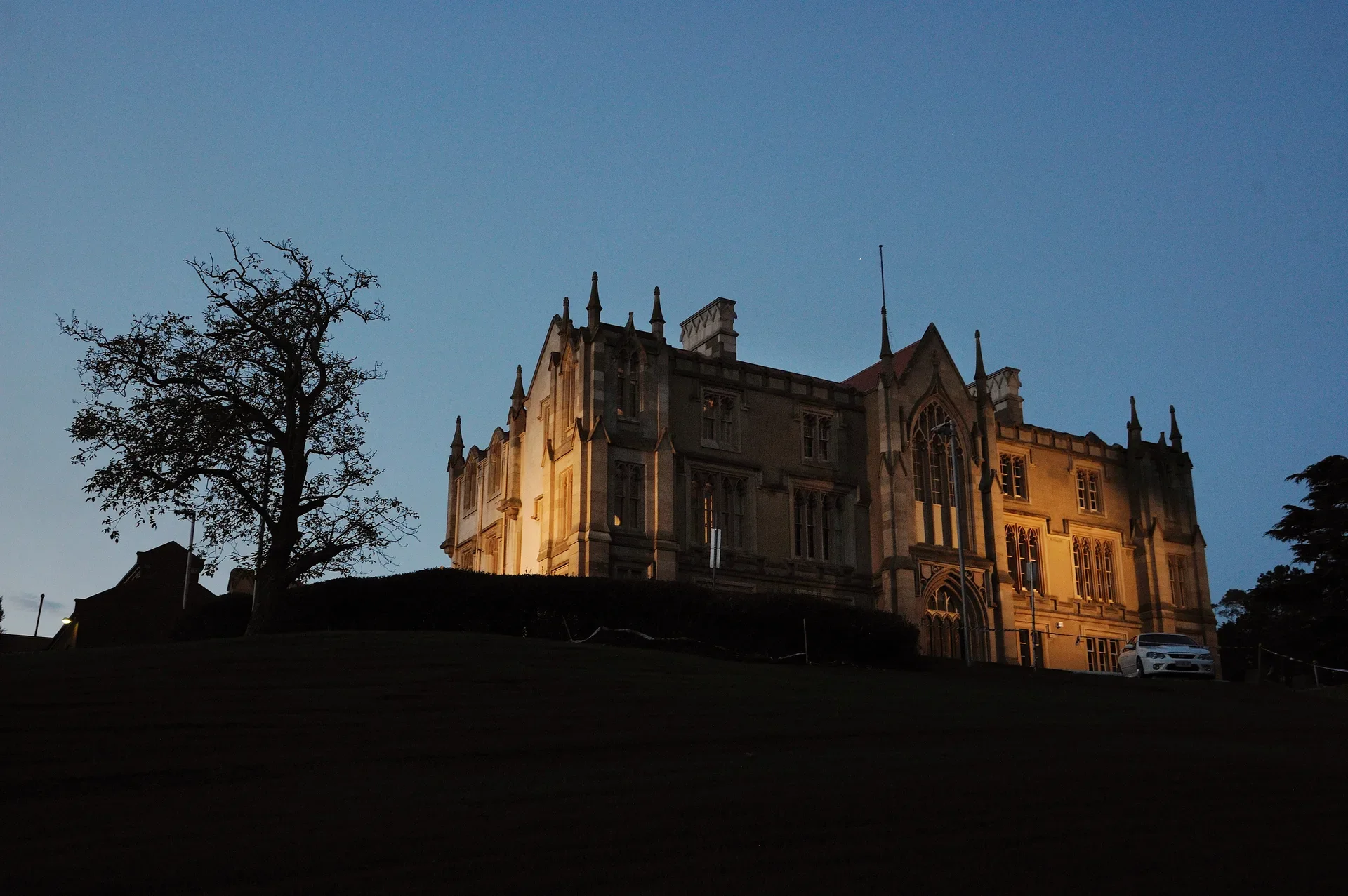 The imposing gothic sandstone building, lit at night.