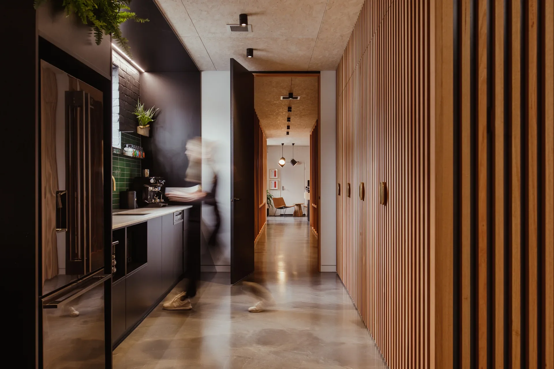 The dark coloured kitchen runs alongside the corridor.