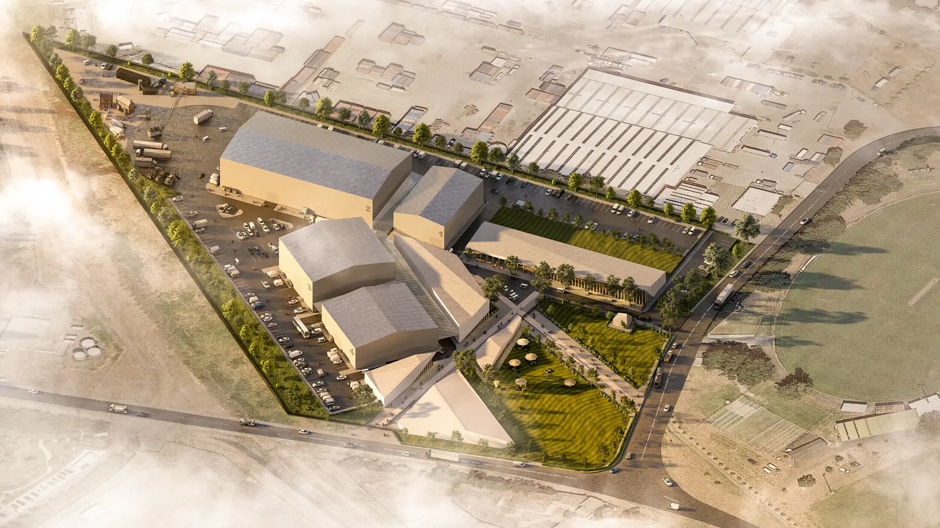 An aerial architectural render looking down over a film studio masterplan composed of large, neutral-toned soundstage volumes arranged around internal streets and courtyards. A central landscaped spine with lawns, trees and gathering spaces connects the buildings, while parking, loading areas and service yards sit to the perimeter. The composition emphasises clear zoning between public-facing green space and the more industrial studio functions.