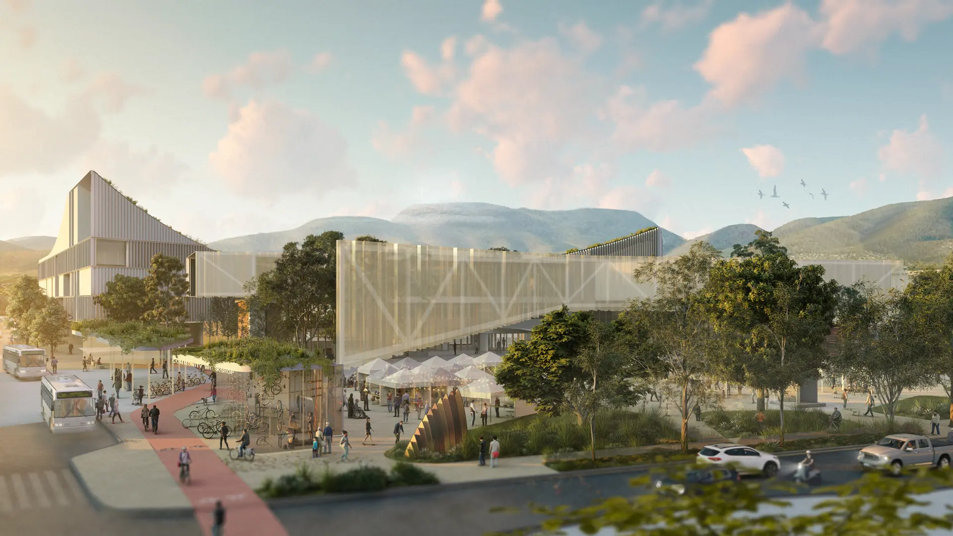 An aerial visualisation of the master plan illustrating the connection to the surrounding roadways. A red shared bike and pedestrian path snakes between the polycarbonate facade of the new library and white fin panelled facade of the buildings behind. Large native trees extend from mature native planting landscaping, with glimpses of market stalls and a bike storage facility in the foreground. Hobart and Glenorchy's hills can be seen in the background, including views of Kunanyi / Mount Wellington at thr rear.