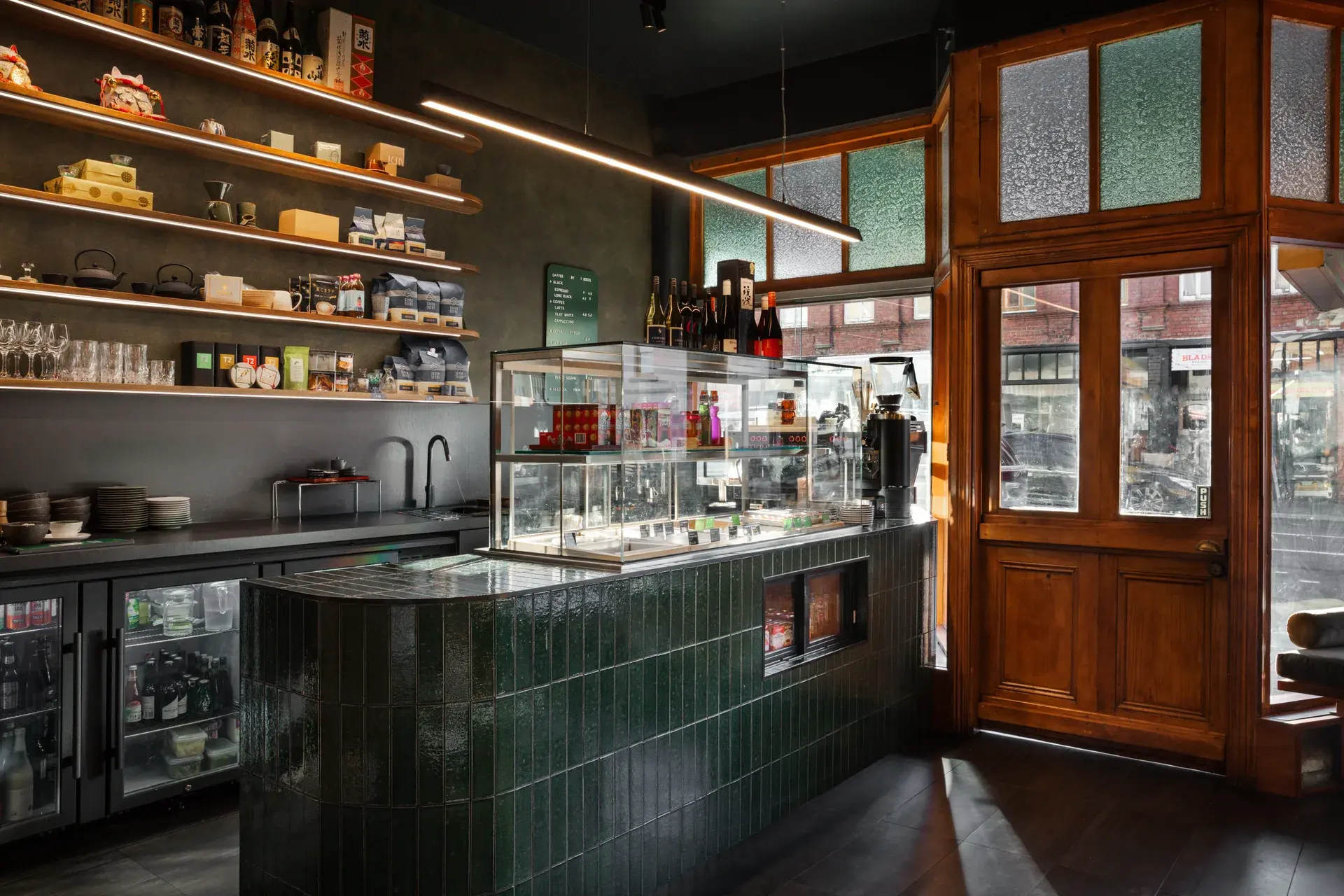 The tiled serving counter sits within the heritage building, drawing from the textured glass panes and timber framework of the existing space.