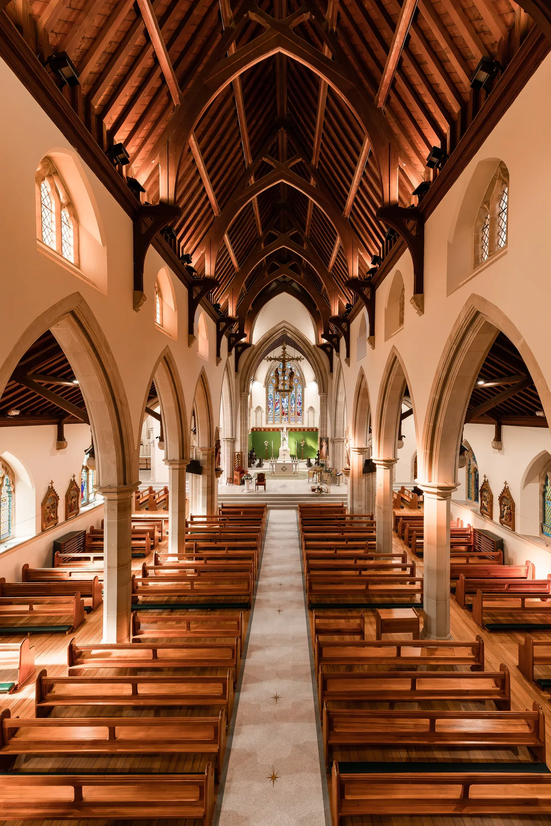 High-angle view of St Mary's Cathedral interior featuring a vaulted timber ceiling, stone arches, and rows of wooden pews leading to a distant altar.