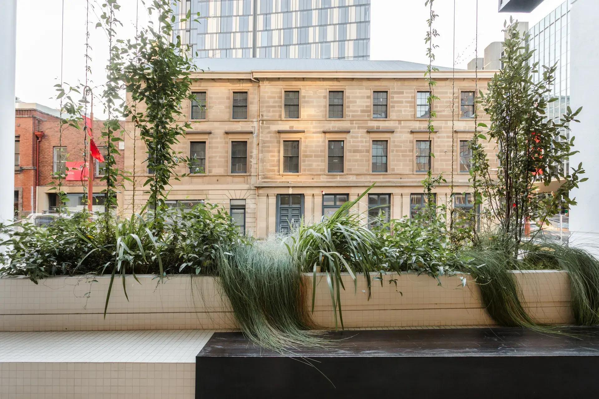 A view from the colonnade looking across Collins Street to a 3 storey sandstone heritage building.