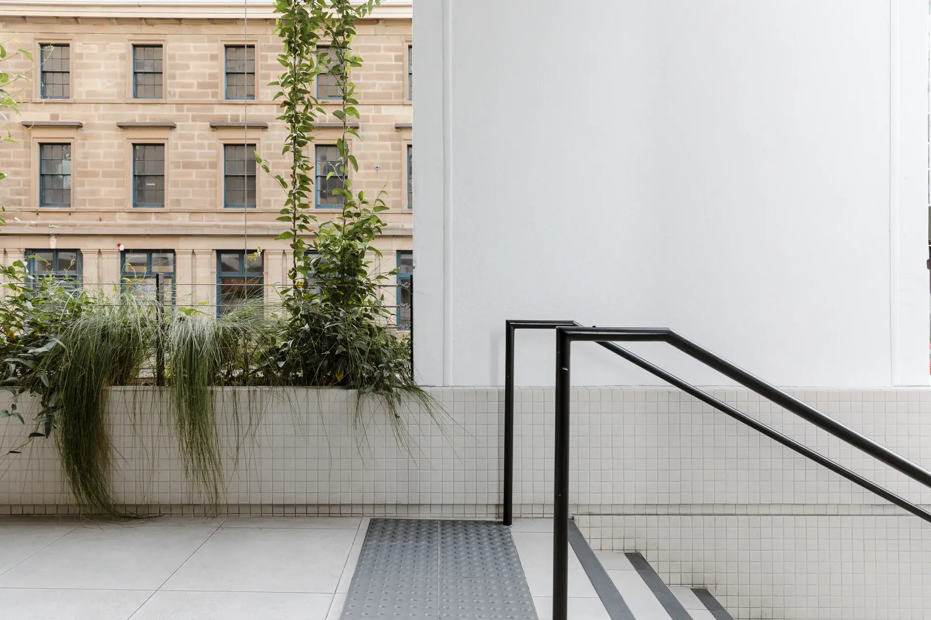 The top of the stair balustrades, with the native planting and neighbouring heritage buildings behind.