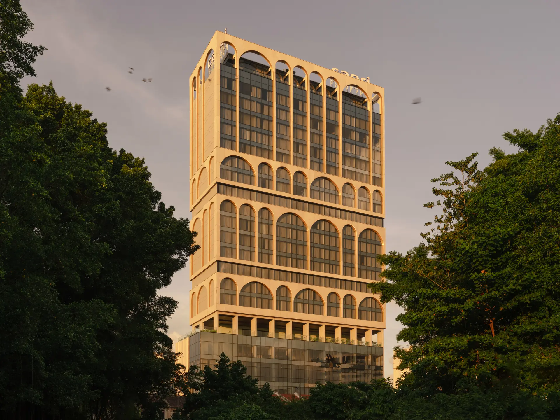 Modern arched high-rise building with glass windows and tan facade