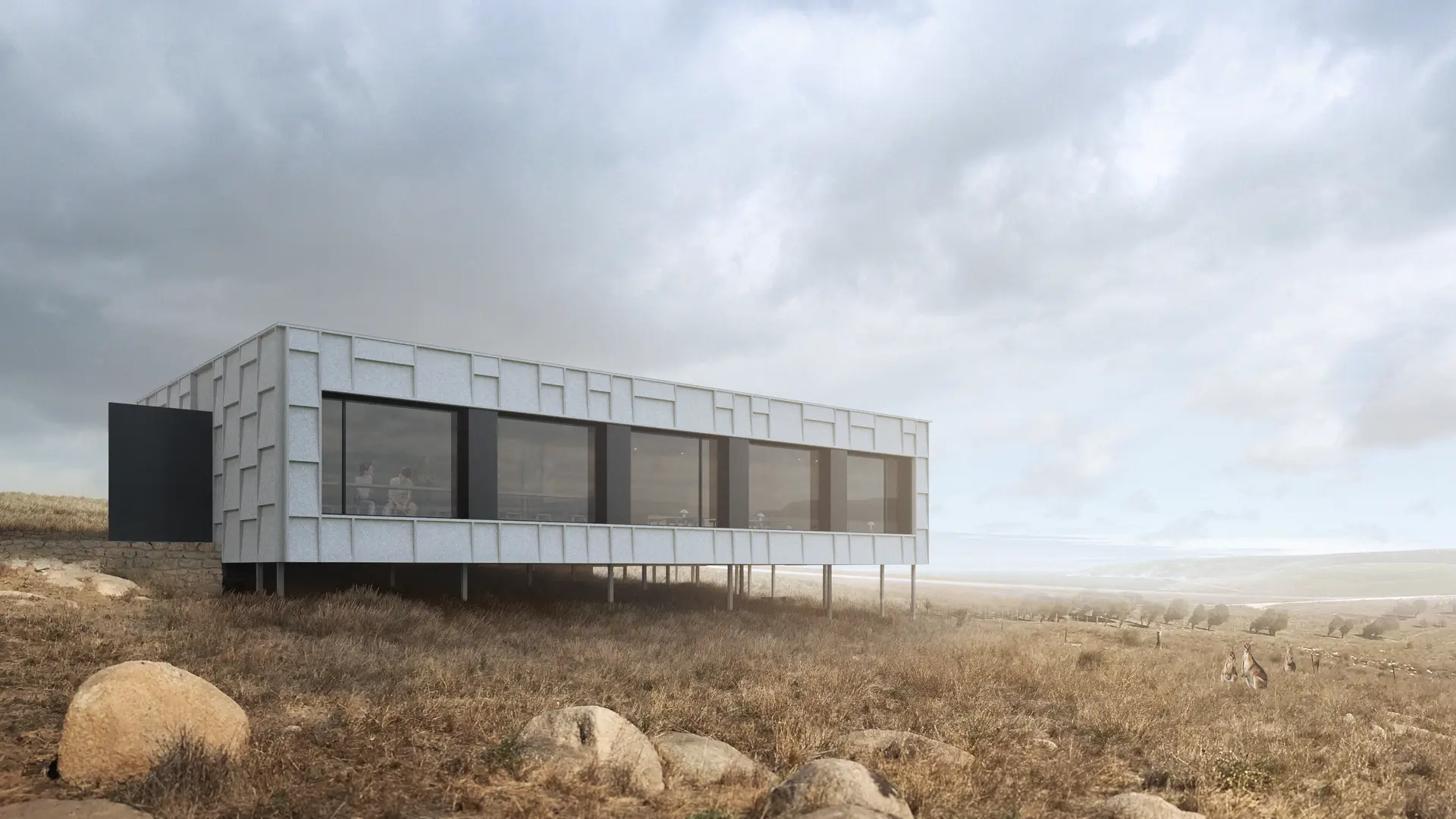 An elongated, elevated pavilion sits lightly within a windswept coastal landscape, clad in pale, panellised metal with a boxy geometric relief pattern. A continuous band of glazing frames expansive views across low scrub and distant coastline, while slender stilt columns below lift the structure above the terrain. Native wallabies can be seen gathering nearby.