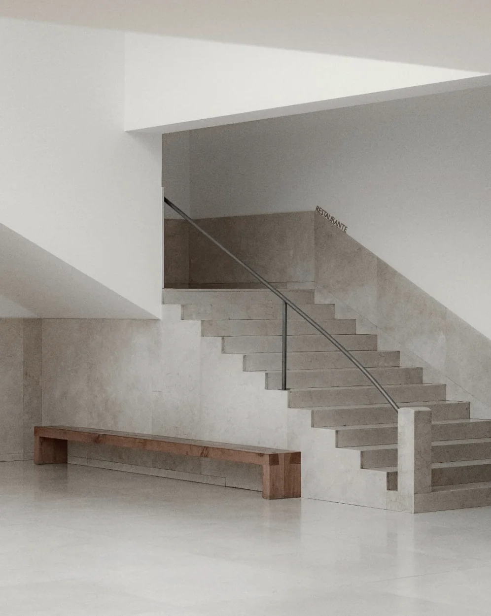 A minimalist architectural interior featuring pale stone stairs, clean white walls, and a simple wooden bench.
