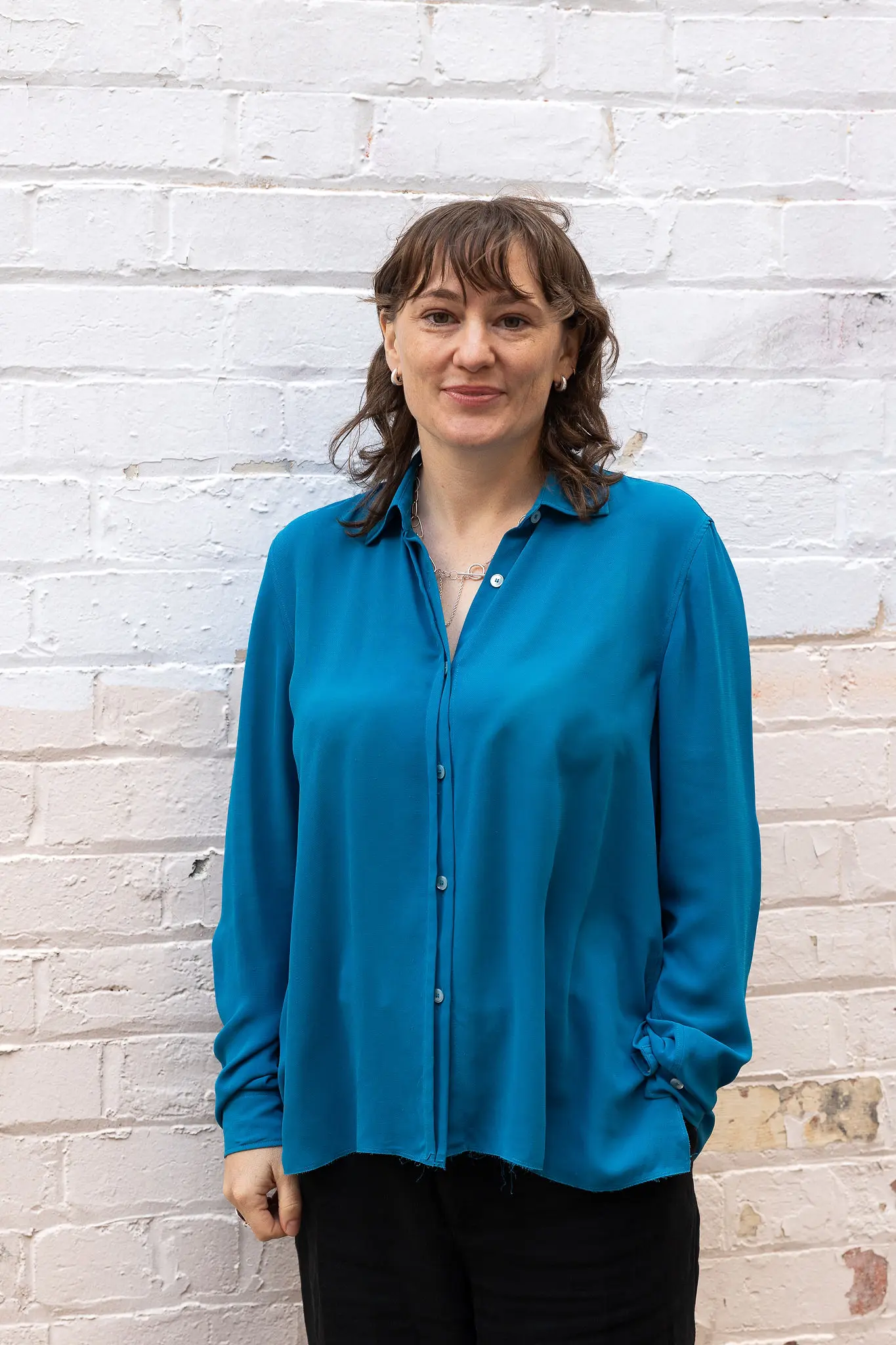 Profile photograph of Senior Architect Priscilla Finn, standing in front of a heritage sandstone wall.